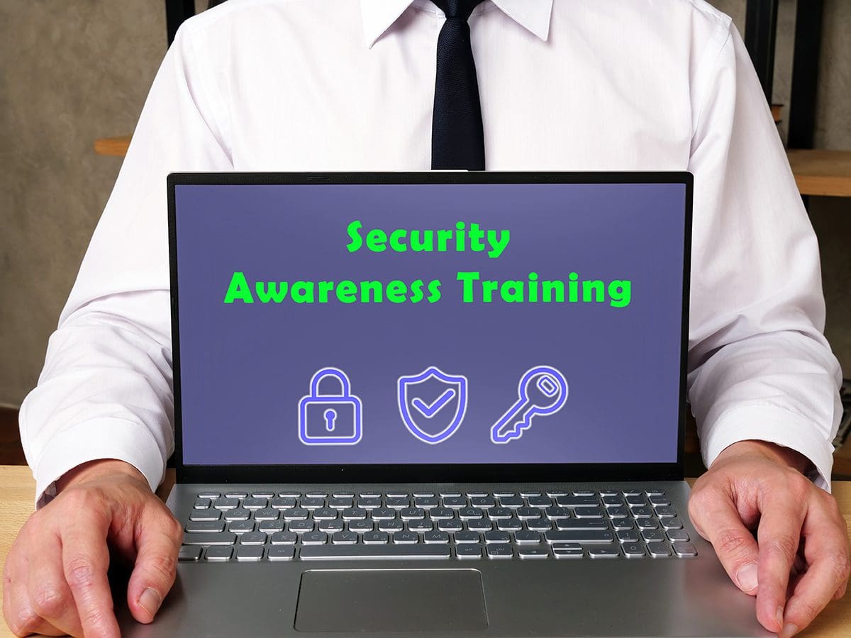 A man in a suit holding a laptop that reads “Security Awareness Training.”